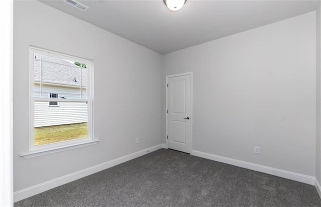 empty room featuring a wealth of natural light, dark carpet, and baseboards