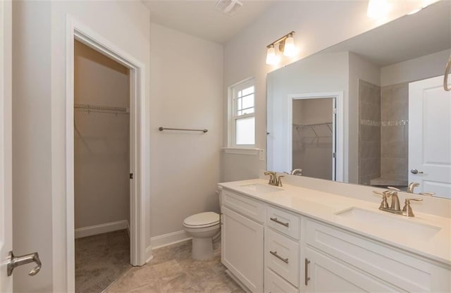 bathroom with a spacious closet, double vanity, and a sink