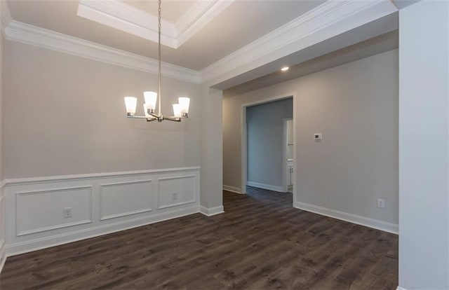 unfurnished dining area with dark wood finished floors, a raised ceiling, wainscoting, ornamental molding, and a notable chandelier