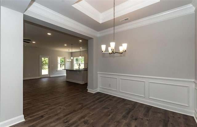 spare room with a chandelier, dark wood-style flooring, a raised ceiling, and crown molding