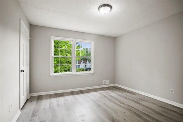empty room with wood finished floors, baseboards, and a textured ceiling