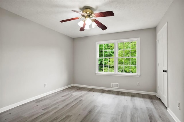 unfurnished room with wood finished floors, a ceiling fan, baseboards, and a textured ceiling