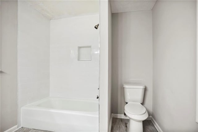 full bath featuring toilet, baseboards, wood finished floors, and bathtub / shower combination