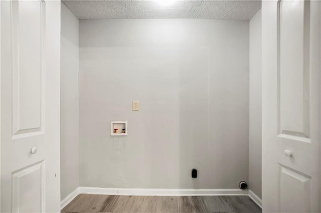 washroom featuring washer hookup, wood finished floors, baseboards, and a textured ceiling