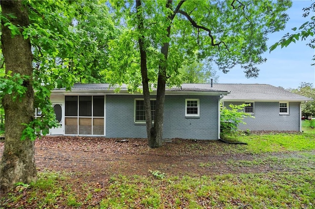 back of property featuring a sunroom and brick siding