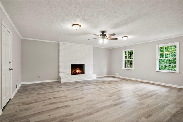 unfurnished living room featuring ornamental molding, ceiling fan, wood finished floors, a textured ceiling, and a fireplace