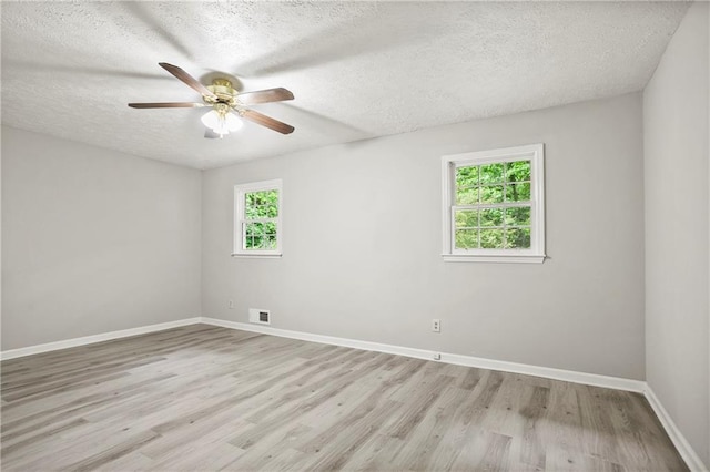 empty room with a ceiling fan, light wood-type flooring, a textured ceiling, and baseboards