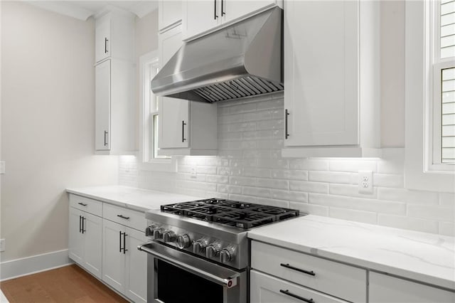 1419 Coretta Bnd, Atlanta, GA 30318 - kitchen featuring under cabinet range hood, high end range, white cabinets, light stone counters, and tasteful backsplash