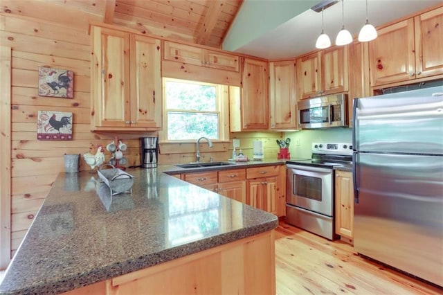 kitchen featuring light wood-style flooring, appliances with stainless steel finishes, a peninsula, light brown cabinetry, and a sink