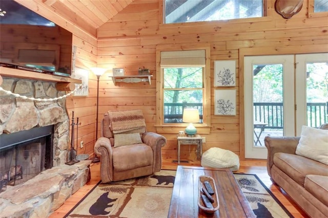 interior space with lofted ceiling, a fireplace, wood finished floors, and wooden walls