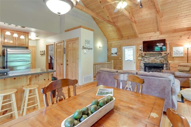 dining area with visible vents, wood ceiling, wooden walls, wood finished floors, and beamed ceiling