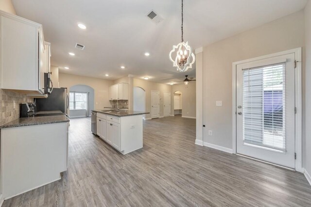 kitchen with arched walkways, a sink, stainless steel appliances, a chandelier, and recessed lighting