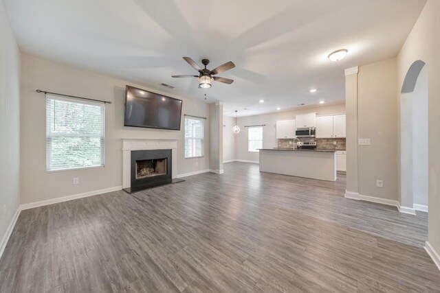 unfurnished living room featuring ceiling fan, wood finished floors, baseboards, and recessed lighting
