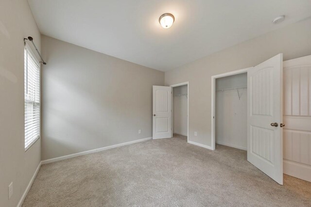 unfurnished bedroom with light carpet and baseboards