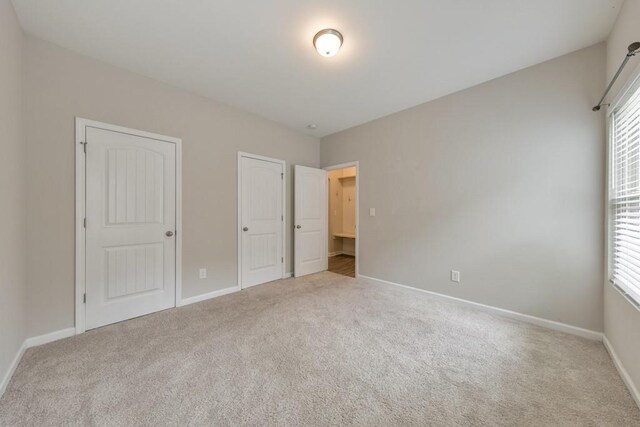 unfurnished bedroom featuring carpet floors, multiple windows, and baseboards