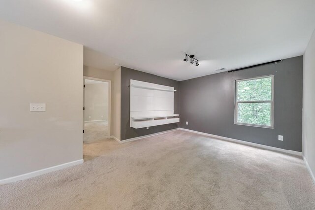 unfurnished room with carpet floors, baseboards, and rail lighting