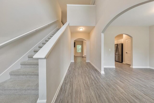 entryway with wood finished floors, stairs, baseboards, and a towering ceiling