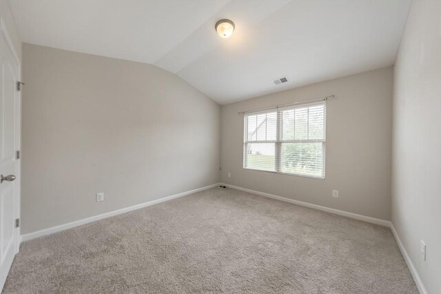 unfurnished room with vaulted ceiling, carpet flooring, and baseboards