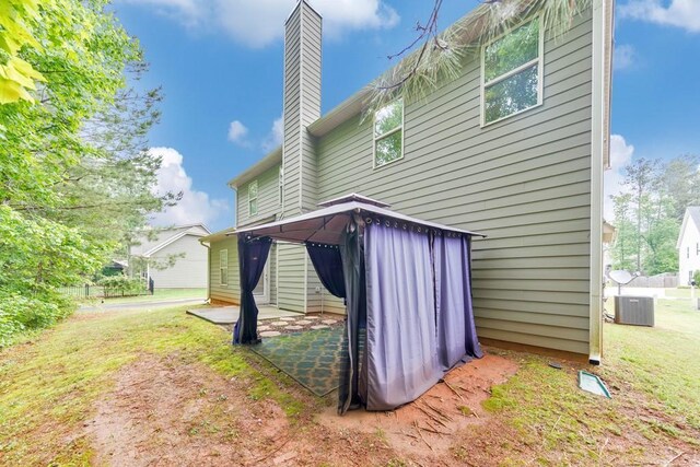 rear view of property with a chimney, a patio, and a gazebo
