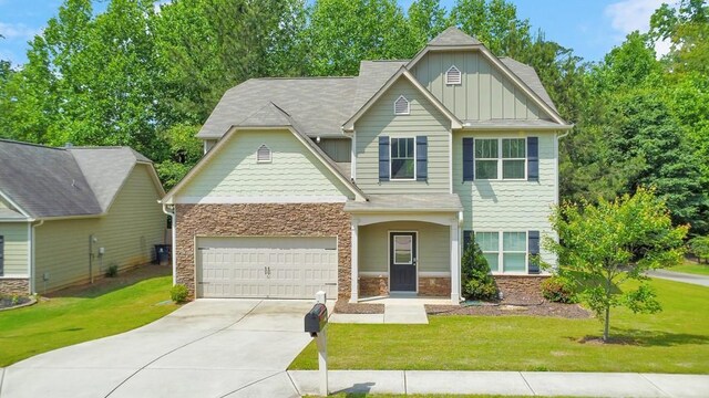craftsman-style home with board and batten siding, a front yard, concrete driveway, stone siding, and an attached garage