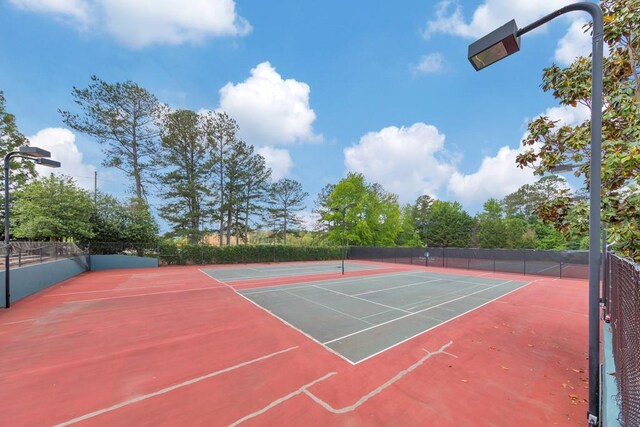view of tennis court featuring fence and community basketball court