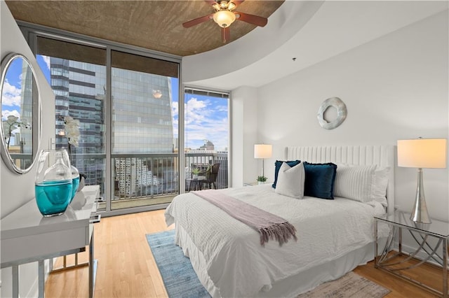 bedroom featuring expansive windows, access to outside, hardwood / wood-style floors, and ceiling fan