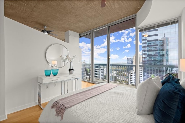 bedroom with access to exterior, hardwood / wood-style flooring, and floor to ceiling windows