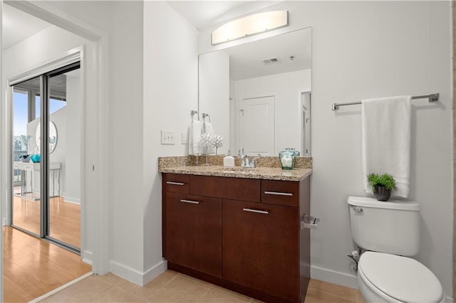 bathroom with toilet, vanity, and wood-type flooring