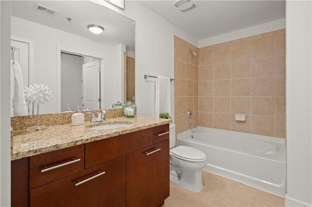 full bathroom with tile patterned flooring, vanity, tiled shower / bath combo, and toilet