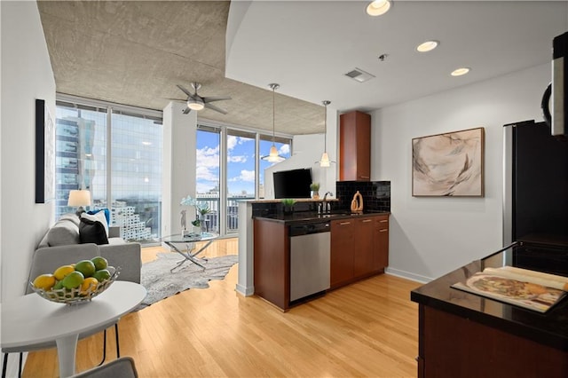 kitchen with stainless steel appliances, decorative light fixtures, floor to ceiling windows, light hardwood / wood-style floors, and kitchen peninsula