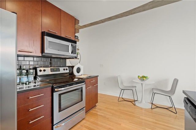 kitchen with backsplash, appliances with stainless steel finishes, and light hardwood / wood-style flooring