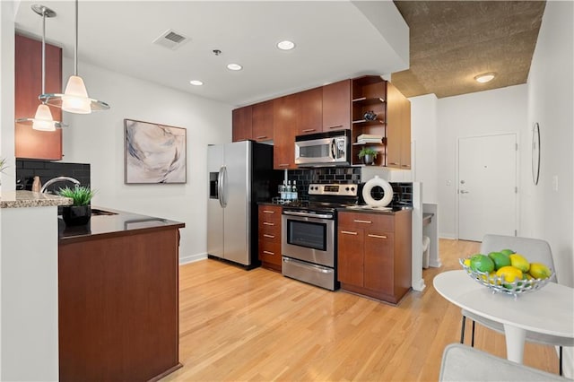 kitchen featuring sink, appliances with stainless steel finishes, hanging light fixtures, light wood-type flooring, and decorative backsplash