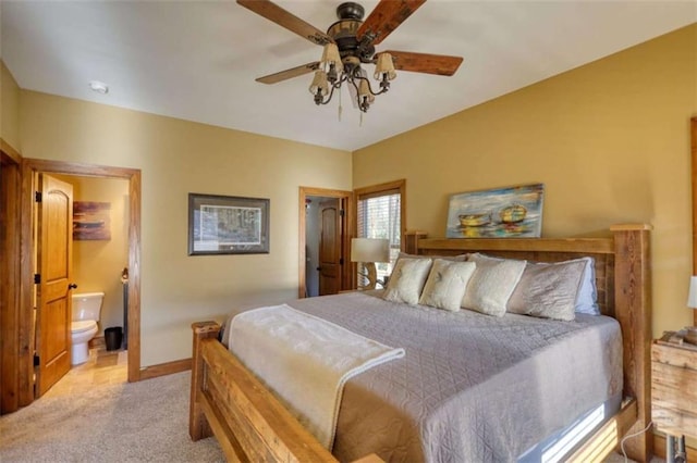 bedroom featuring baseboards, ensuite bath, a ceiling fan, and light colored carpet