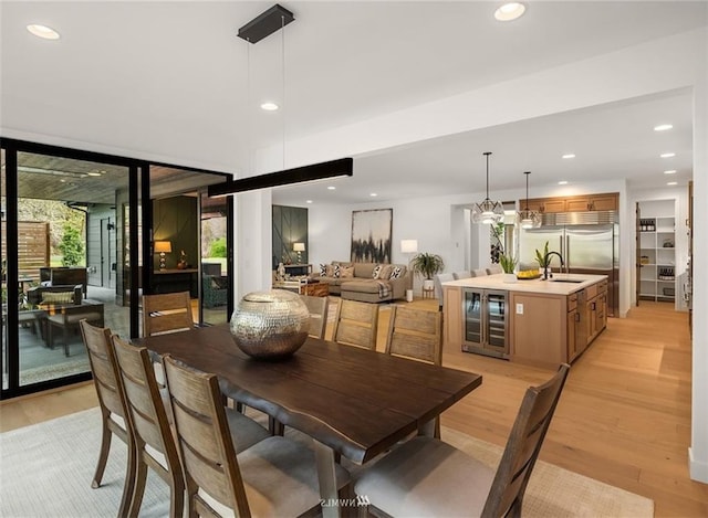 dining room with sink, wine cooler, and light wood-type flooring