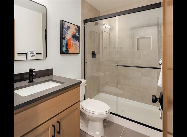 bathroom featuring tile patterned floors, vanity, toilet, and a shower with shower door