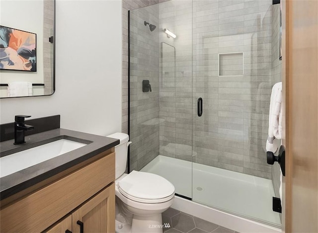 bathroom featuring walk in shower, vanity, toilet, and tile patterned flooring