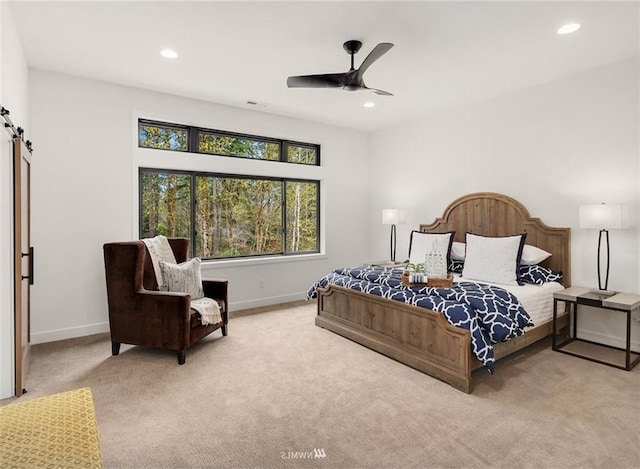 bedroom with a barn door, light colored carpet, and ceiling fan