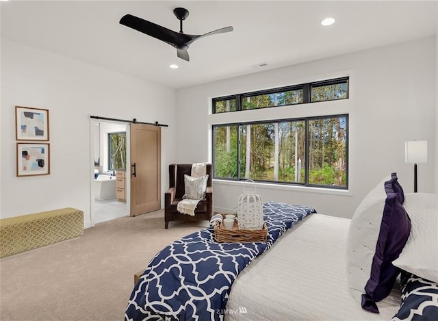 carpeted bedroom featuring ceiling fan, a barn door, and ensuite bath