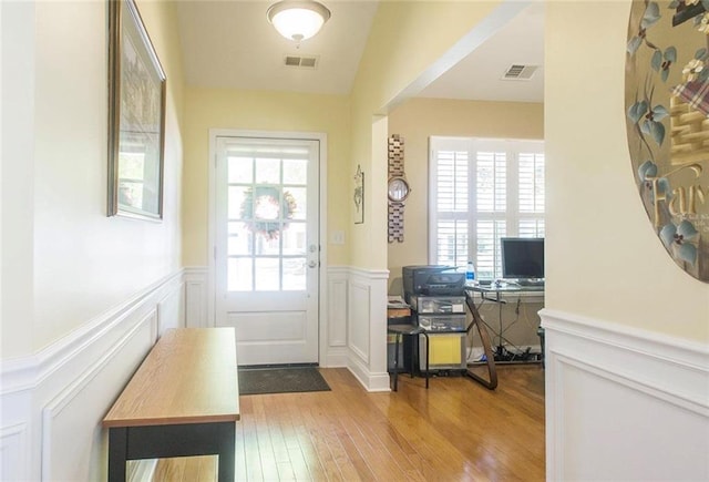 doorway featuring a healthy amount of sunlight, light hardwood / wood-style flooring, and vaulted ceiling