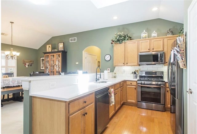 kitchen featuring kitchen peninsula, appliances with stainless steel finishes, decorative backsplash, sink, and decorative light fixtures