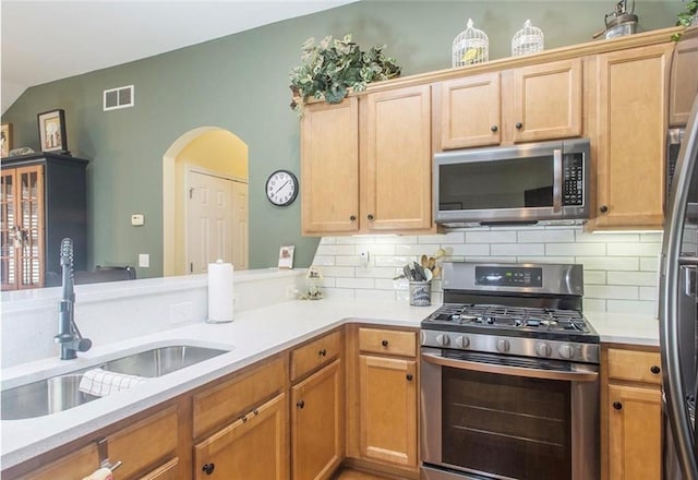 kitchen featuring kitchen peninsula, backsplash, stainless steel appliances, and sink