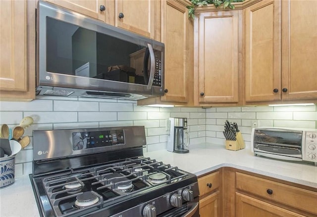 kitchen with black gas range, decorative backsplash, and light stone countertops