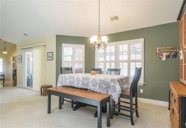 dining room with vaulted ceiling, light colored carpet, and a chandelier