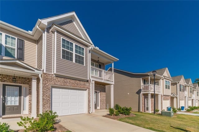 view of property featuring a balcony, a front yard, and a garage