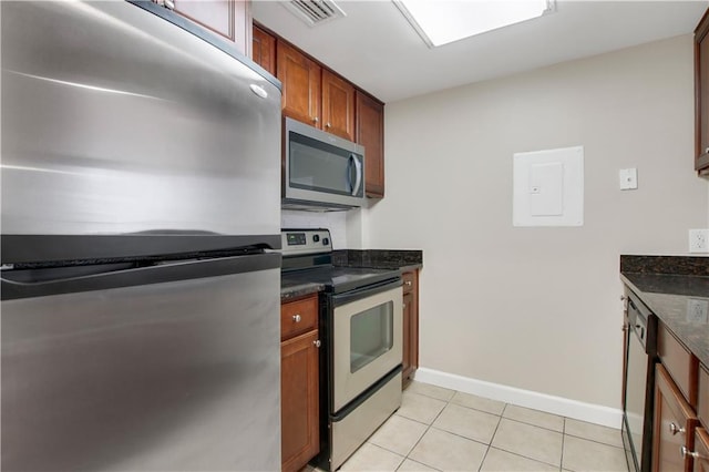 kitchen featuring dark stone counters, electric panel, stainless steel appliances, and light tile patterned floors