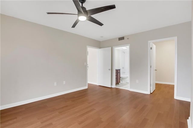 unfurnished bedroom featuring ceiling fan, hardwood / wood-style flooring, ensuite bath, and a spacious closet