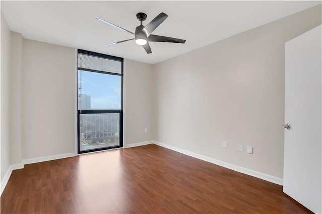 empty room featuring a wall of windows, ceiling fan, and dark wood-type flooring