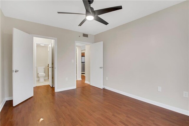 unfurnished bedroom featuring refrigerator, ceiling fan, dark hardwood / wood-style flooring, and ensuite bath