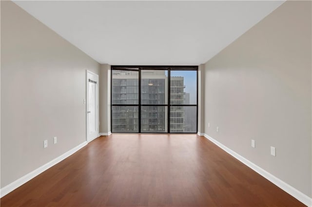 unfurnished room featuring floor to ceiling windows and hardwood / wood-style floors