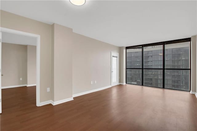 empty room with dark hardwood / wood-style flooring and expansive windows